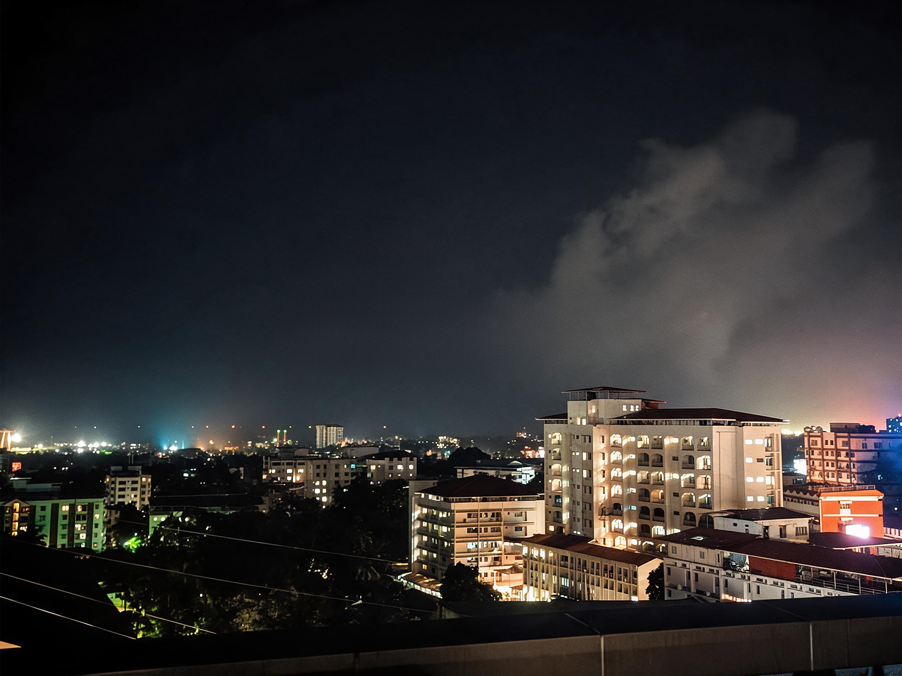 Mangalore city skyline lit up at night under a cloudy sky